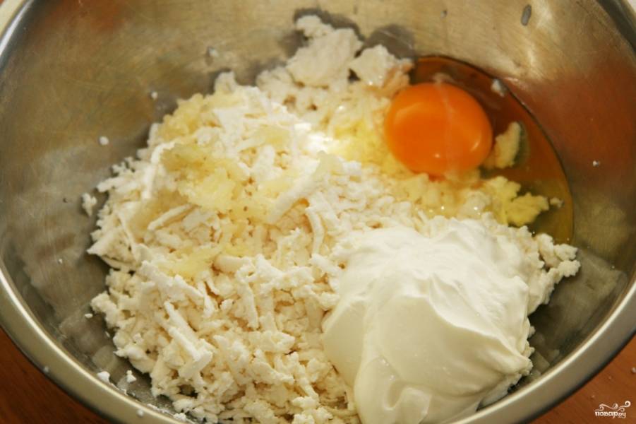 Отправьте тесто в холодильник, займитесь начинкой. Смешайте яйцо со сметаной. Натрите сыр, а чеснок продавите на чесноковадке. По вкусу добавьте немного соли. Перемешайте всё вилкой.