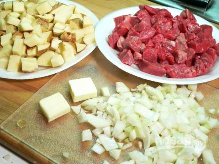 Мясо и картофель помойте. Нарежьте мясо небольшими кусочками. Картофель не нужно чистить, порежьте его кубиками вместе с кожурой. Лук мелко нашинкуйте.