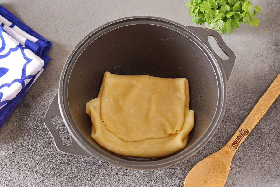 Затем раскатайте тесто в тонкий пласт, толщиной около 2-3 мм. На дно казана налейте масло. Перенесите тесто в казан, подвернув края к середине как на фото.