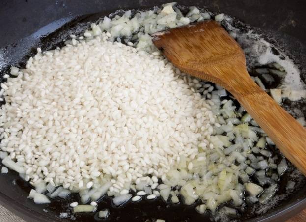 К полупрозрачному луку добавляем рис, жарим все вместе 1-2 минуты. 