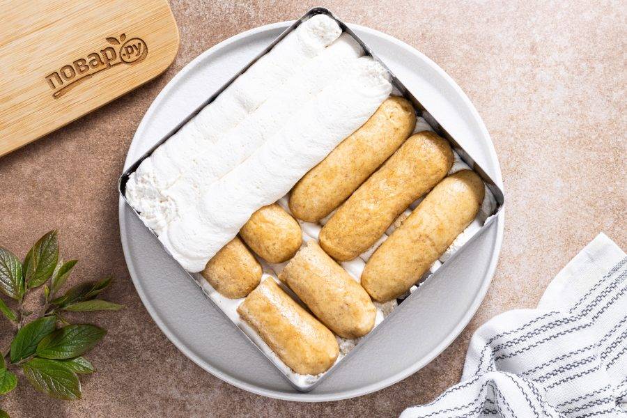 Выложите второй слой печенья пропитанного кофе. Покройте второй половиной крема.