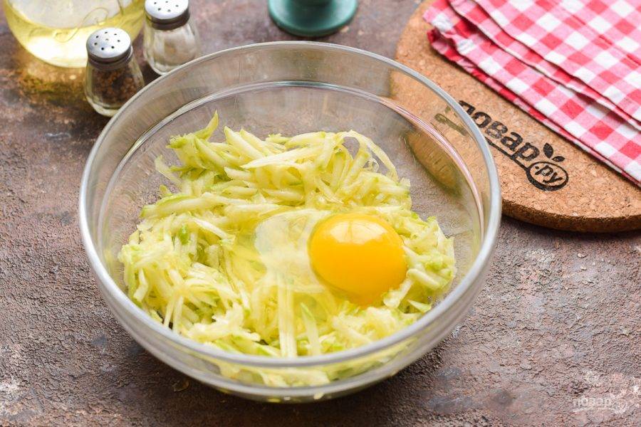 В миску с кабачками добавьте куриное яйцо, всыпьте соль, перец, сушеный чеснок.
