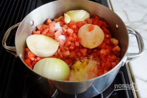4. После этого в большую кастрюлю выложите соль, сахар, помидоры, очищенный чеснок и половинки лука.