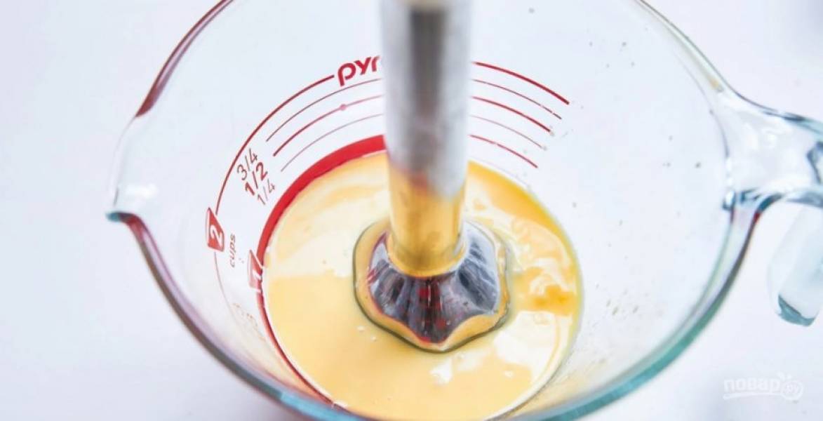 2.	Добавьте в емкость с маслом яичные желтки и сразу же смешайте до однородной массы с помощью погружного блендера или насадки венчик.