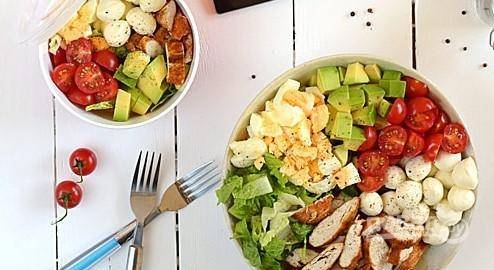 Нарежьте авокадо, яйца и помидорки. Уложите ингредиенты вместе с салатом и курицей в салатницу без смешивания. Поперчите их.