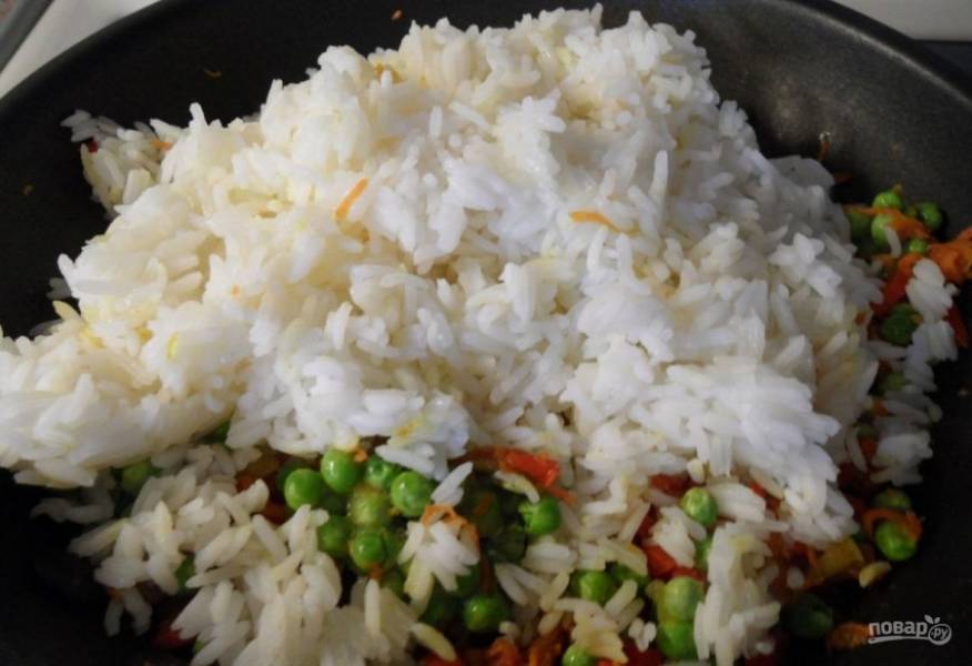 Затем добавьте в сковороду лук, перец и морковь. Жарьте овощи до прозрачности лука. Потом внесите горошек и всё перемешайте. Также добавьте отварной рис.