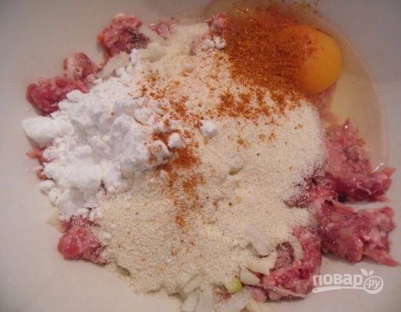 3. Вбейте в фарш яйцо, добавьте крахмал и манную крупу. Посолите по вкусу, всыпьте специи. 