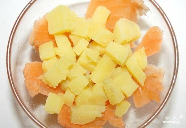 Порежьте форель на некрупные кусочки и выложите их на дно тарелки. Отварите картофель в мундире. Посолите его. После того, как картофель сварится, остудите и очистите  его. Порежьте на мелкие кубики и положите поверх рыбы.