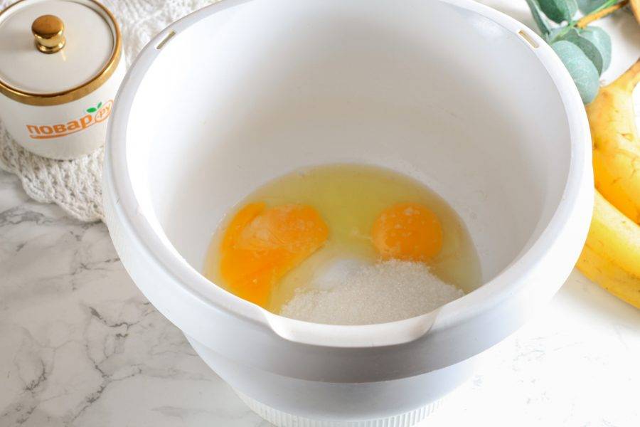 Вбейте куриные яйца в чашу миксера или кухонного комбайна, всыпьте 100 грамм сахарного песка и соль. Взбейте примерно 4-5 минут в пышную пену.