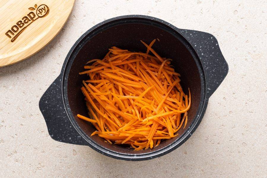 Морковь натрите на терке для моркови по-корейски. Отправьте ее следом в кастрюлю и снова доведите до кипения.