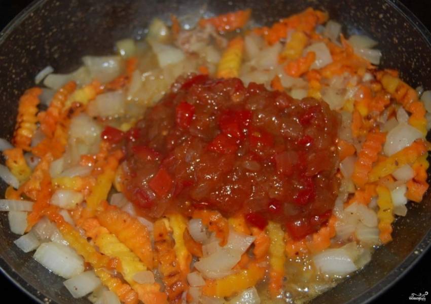 Когда лук стал прозрачным, добавьте в поджарку томатную пасту. Размешайте овощи вместе с томатной пастой. Потушите 1-2 минуты.