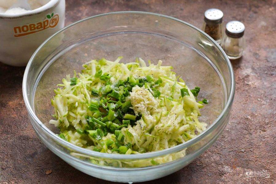 Нарежьте зеленый лук мелко и добавьте в кабачок. Также очистите и натрите на мелкой терке чеснок, добавьте к кабачку.