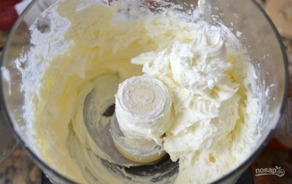 В комбайне взбейте сахар со сливочным сыром. Затем добавьте яйца, сметану, молоко и ванилин. Продолжайте взбивать. А в конце всыпьте муку. Ещё раз перемешайте. Распределите крем по остывшей основе. Отправьте изделие в духовку.