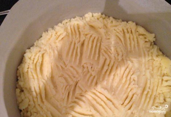 Приготовьте форму для выпечки и застелите её пергаментной бумагой. Уложите на её дно картофельное пюре.