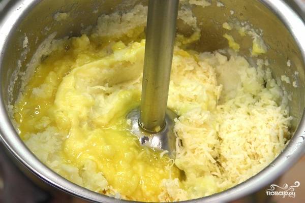 3. Снимите картофель с огня, слейте с него воду, разомните в пюре. Добавьте сливочное масло и желтки. Натрите немного сыра (горсть оставьте). Все как следует перемешайте. 
