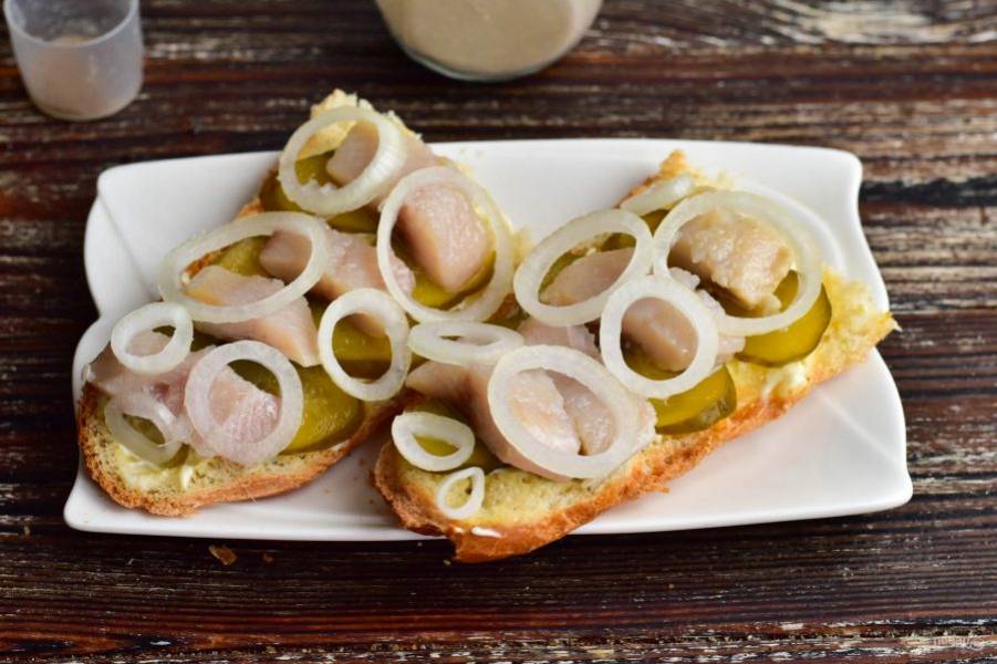 На рыбу выложите репчатый лук, который нарежьте кольцами.