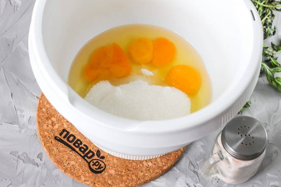 Куриные яйца вбейте в чашу кухонного комбайна или в емкость для миксера. Всыпьте туда же соль, сахар и взбейте все содержимое в течение 3-5 минут до увеличения в 2-3 раза и побеления.