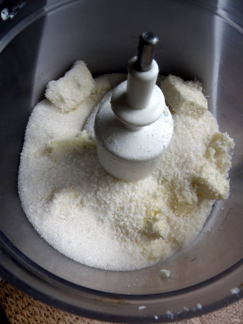 Охлажденное масло необходимо нарезать кусочками и поместить в чашу комбайна. Добавьте сахар, ванилин, соль и кокосовую стружку. В пульсовом режиме измельчите в крошку.