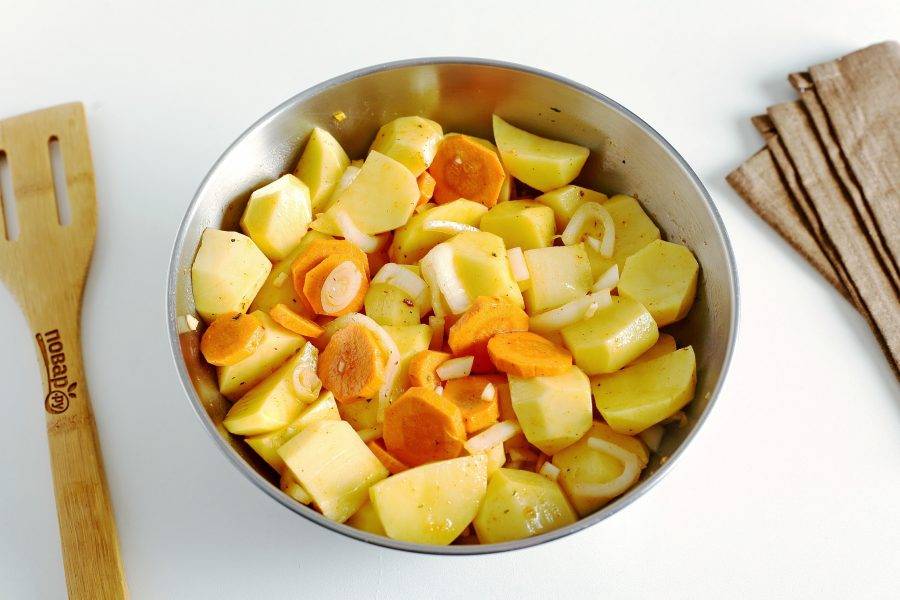В глубокой миске соедините нарезанный картофель, лук, чеснок и морковь (нарезка может быть любая, но не слишком мелко). Добавьте соль, специи, растительное масло и все хорошо перемешайте.