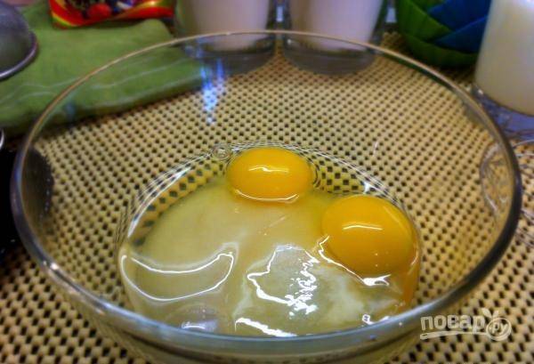 Возьмите глубокую стеклянную миску и всыпьте в нее сто грамм сахара. Затем в нее же вбейте два сырых куриных яйца. 