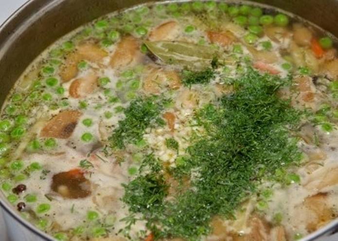 И бросьте в суп зеленый горошек. Добавьте лавровый лист, перец горошком, мелко рубленный чеснок и зелень укропа. Затем перемешайте суп. 