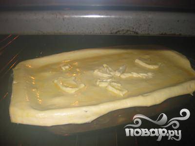 Переложите мясо в противень для выпечки (глубокий). Затем, накройте слоёным тестом, так чтобы оно заступало за края и смажьте яйцом поверхность. Поместите в духовку на 25 минут.