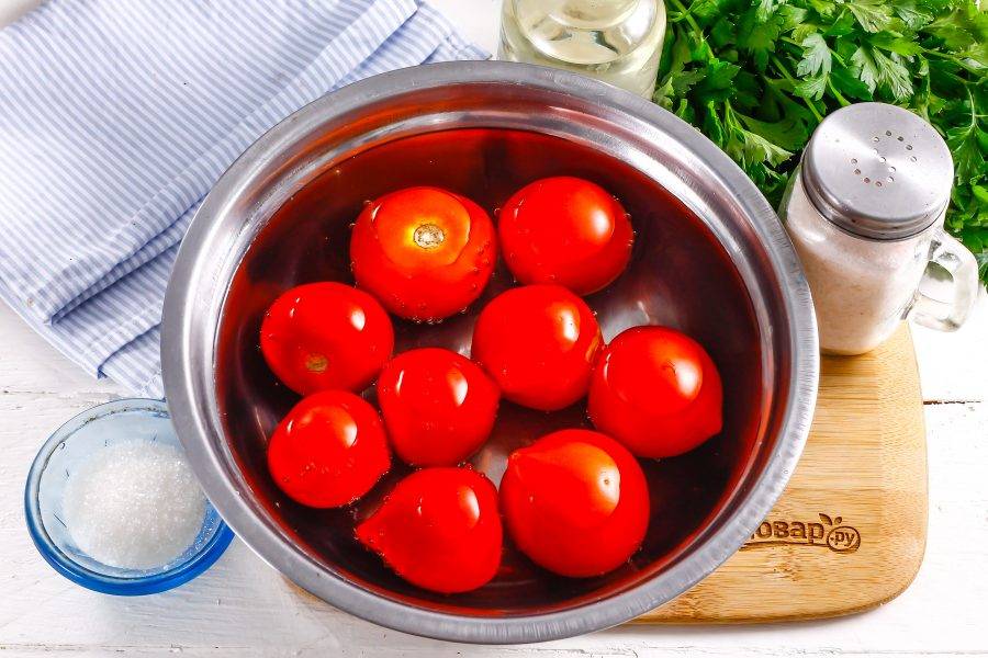 Помидоры промойте в воде и выложите в глубокую емкость. Вскипятите воду в чайнике и залейте ей томаты, оставляя их в кипятке на 10 минут. После чего с каждого из них снимите кожуру, не вырезая сердцевинку.