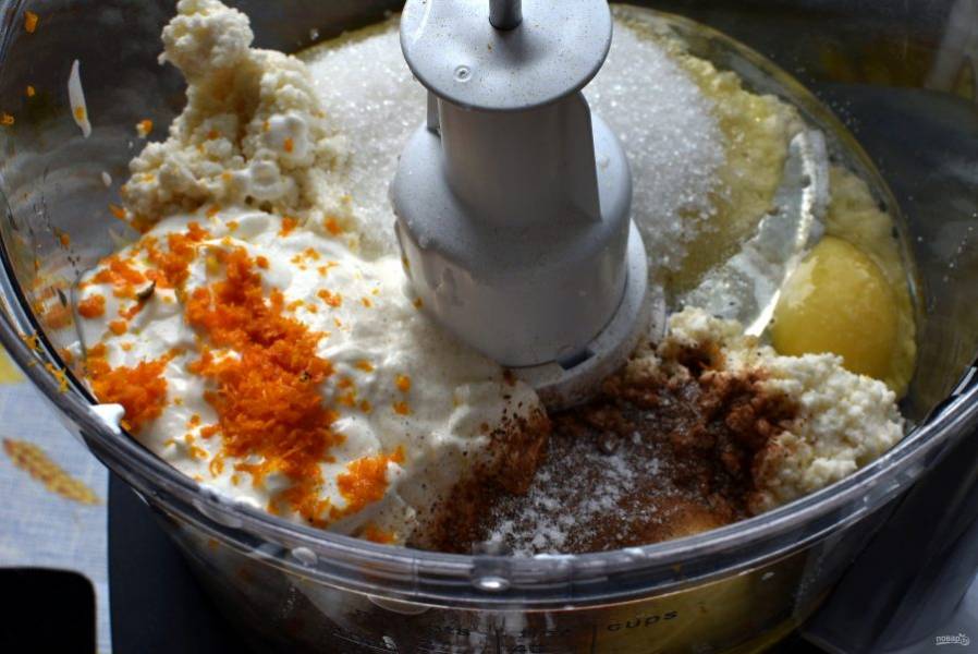 В чашу комбайна выложите творог, сахар, яйца, сметану, цедру и пряности. Добавьте щепотку соли и пробейте в пульсовом режиме до однородности.

