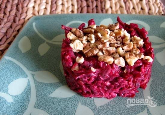 Посолите салат по вкусу. Выложите его в тарелки при помощи кулинарного кольца. Украсьте орехами. Приятной дегустации!