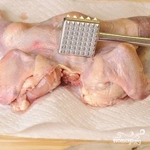 2. Острым ножом разрежьте цыпленка по центру грудки, "разверните" и выложите срезом вниз на донышко. Слегка отбейте цыпленка молоточком.