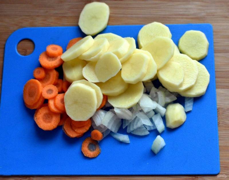 Очистите овощи для супа и нарежьте ломтиками. В процеженный бульон опустите картофель, морковь и лук. Варите до полуготовности.
