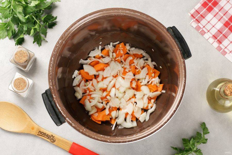 В чашу мультиварки налейте масло и установите режим «Жарка». Когда масло нагреется, выложите нарезанные произвольно лук и морковь. Готовьте периодически помешивая около 5 минут.
