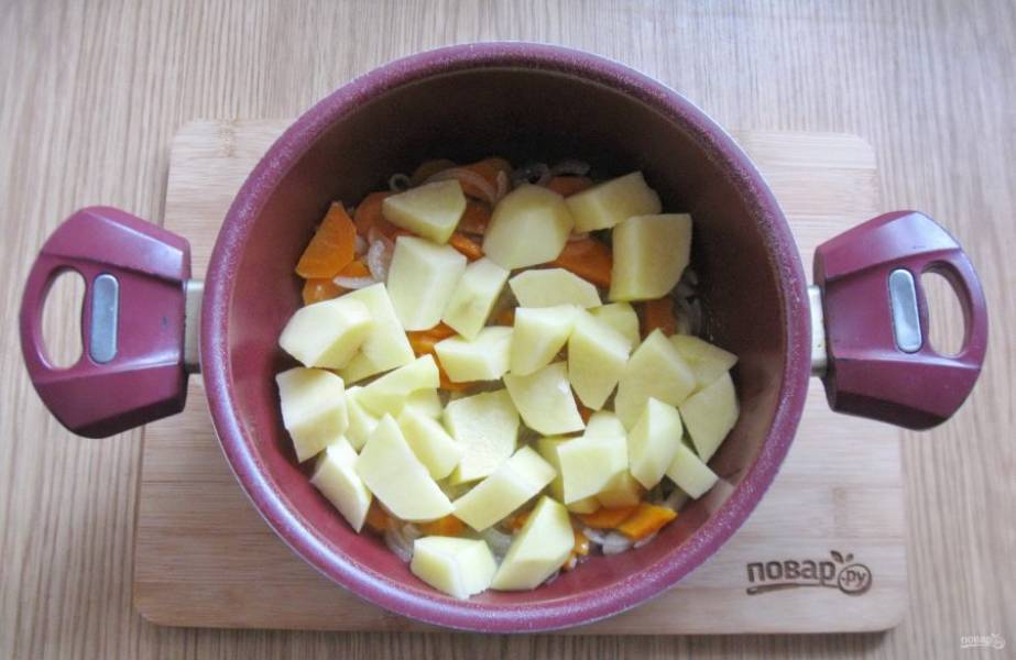 Налейте подсолнечное масло и тушите морковь с луком, периодически перемешивая 7-8 минут. После картофель очистите, помойте и нарежьте не очень мелко. Выложите в кастрюлю.