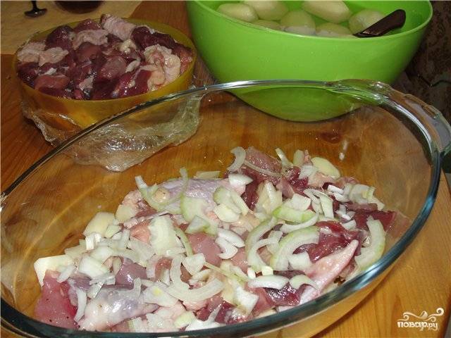 Курицу промываем под холодной водой, а затем нарезаем на небольшие кусочки, посыпаем их солью и перцем. Выкладываем их в жаропрочную посуду. Лук чистим и нарезаем полукольцами, выкладываем на курицу.