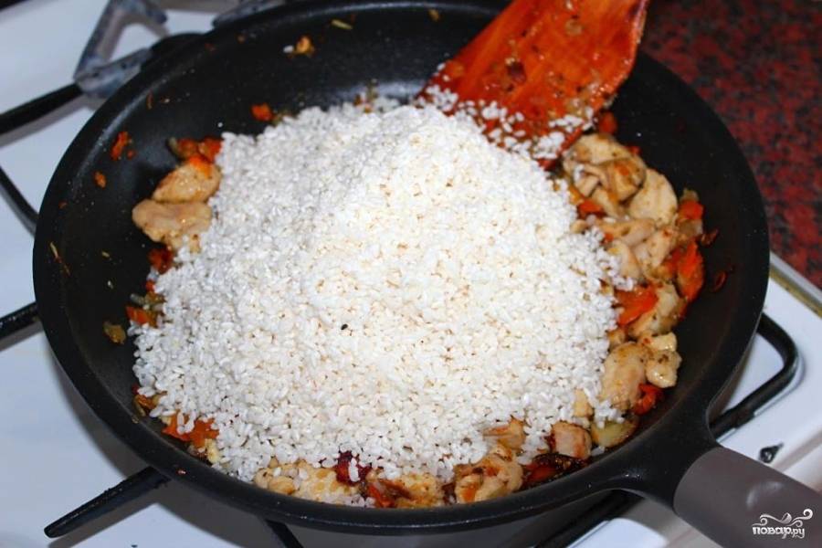 Слить воду с риса и добавить его в сковороду с мясом. Воткнуть целую головку чеснока, посыпать специями (зиру можно добавить вместе с морковью, чтобы обжарилась), посолить, влить 2 стакана воды, закрыть крышкой и томить на самом медленном огне до готовности риса. 