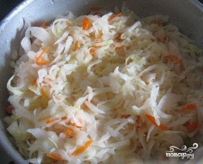 Квашеную капусту слегка промоем и добавим в чугунок к обжаренному мясу, добавим обжаренные лук и морковь, соль и молотый перец. Наливаем примерно стакан горячей воды.