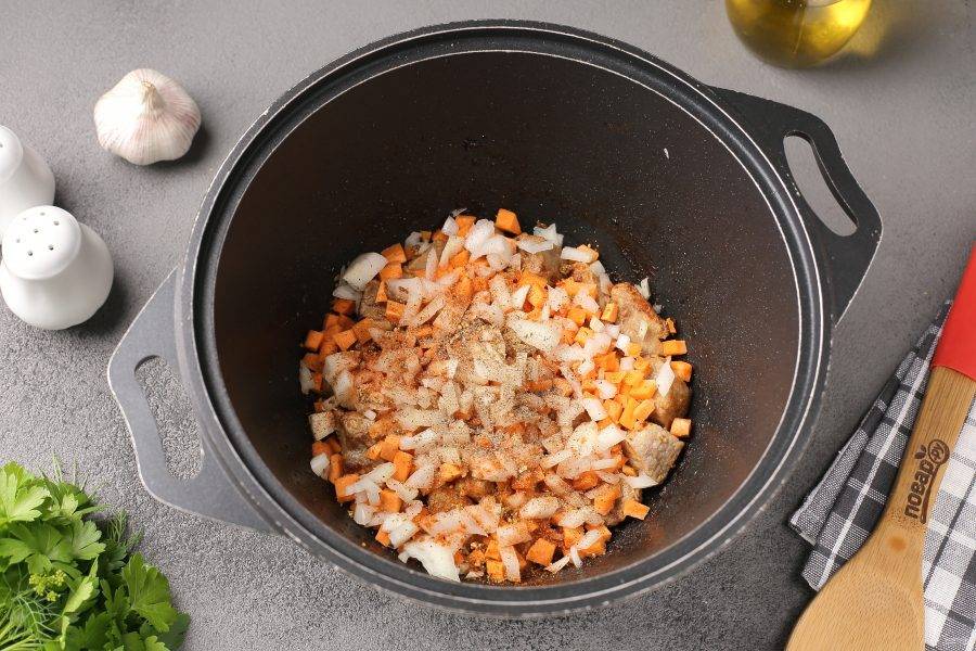 Добавьте нарезанные кубиками лук и морковь, соль и специи по вкусу. Перемешайте и обжарьте мясо с овощами в течение 5 минут.