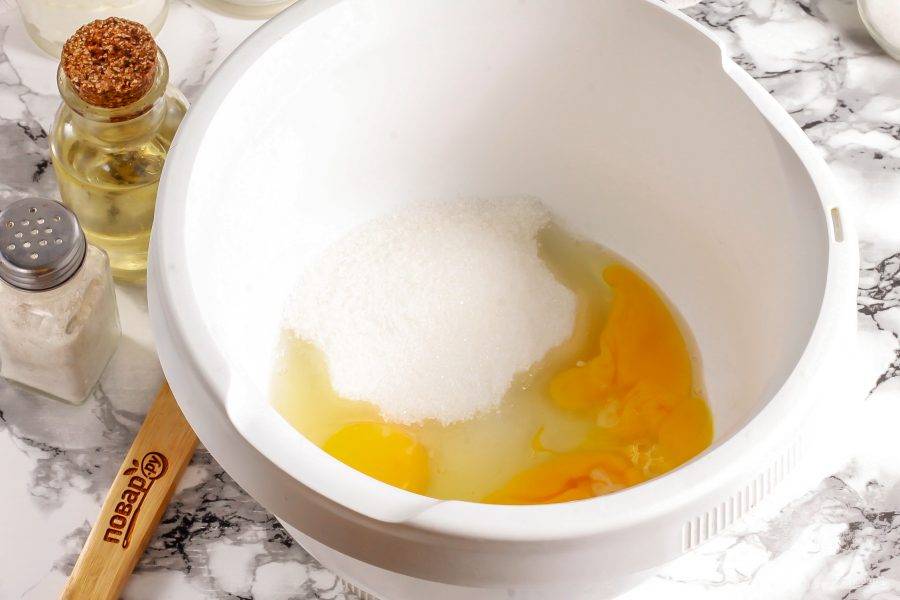 Куриные яйца вбейте в чашу кухонного комбайна или в глубокую емкость для миксера. Всыпьте туда же соль и сахарный песок. Можно добавить немного ванильного сахара или другого ароматизатора для придания аромата бисквиту. Взбейте все примерно 3-5 минут в пышную пену.