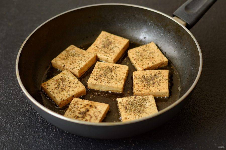 Тофу нарежьте на ломтики. Обмакните в соевый соус, затем посыпьте итальянскими травами и чёрным перцем. Обжарьте тофу на среднем огне до румяной корочки. 