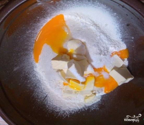 2.	В миску насыпаем муку, добавляем 130 грамм сахара, ванильный сахар. Масло заранее отправляем в холодильник, а затем натираем на крупной терке 180 грамм, добавляем желтки и соду, гашенную уксусом. Замешиваем тесто, после чего заворачиваем его в пленку и ставим в холодильник на полчаса.