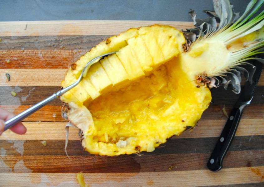 2. Мякоть ананаса в двух половинках нарежьте кубиками и затем при помощи ложки выберите.