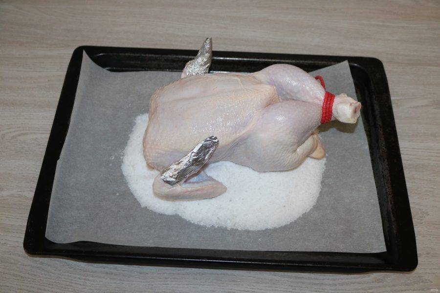 Выложите курицу на соль. Отправьте в разогретую до 180 градусов духовку.