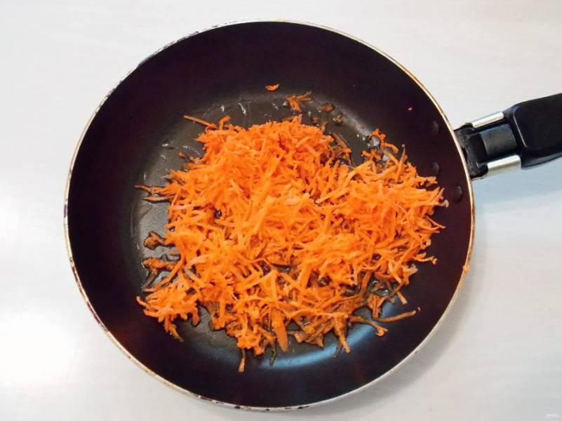 Морковь очистите, сполосните и натрите на мелкой терке. В сковороду налейте растительное  масло и нагрейте на среднем огне. Добавьте в сковороду морковь.