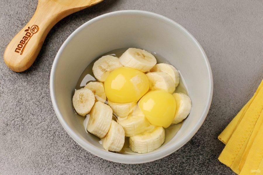 Снимите с банана шкурку и нарежьте кружочками. Переложите в глубокую миску и добавьте яйца.