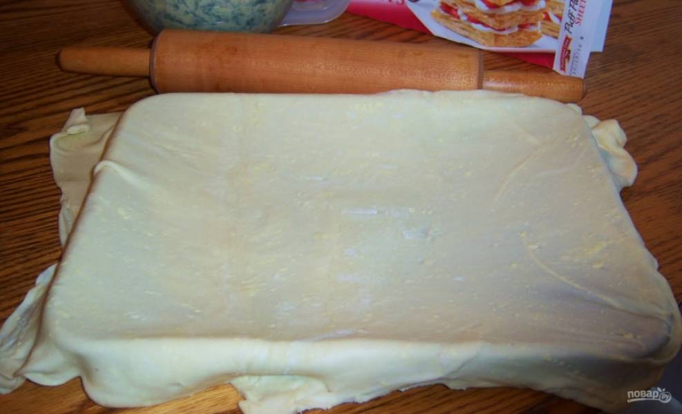 Смажьте форму для выпечки сливочным маслом. 
Раскатайте тесто слоеное и выложите в форму, чтобы края свисали. Смажьте тесто топленным сливочным маслом. 