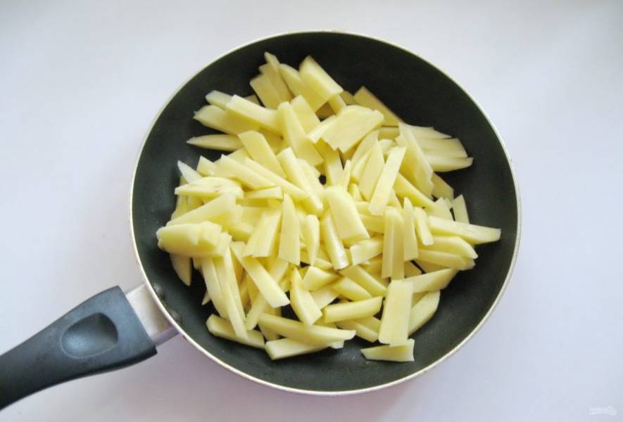 Картофель очистите, помойте и нарежьте соломкой. Выложите в сковороду с подсолнечным маслом.