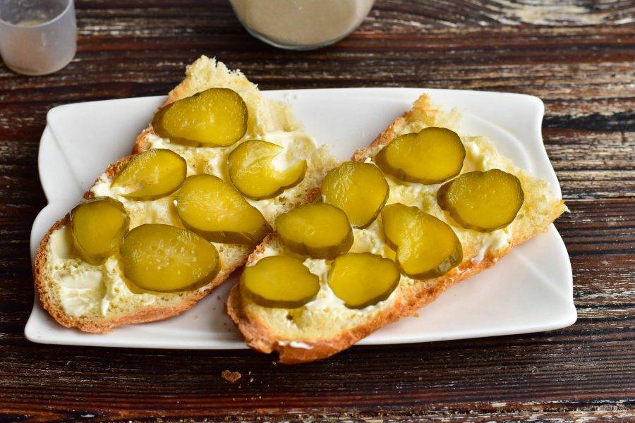 Смажьте майонезом и выложите соленый огурец, который нарежьте тонкими кружочками.