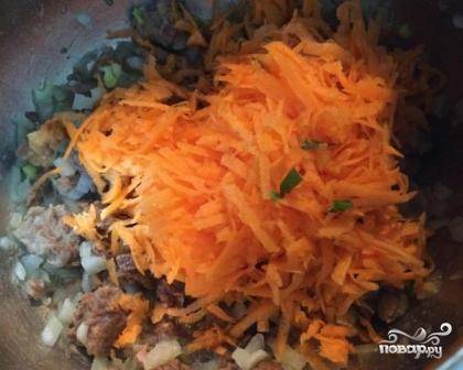 Очищаем морковь, натираем её на средней или крупной терке. Добавляем морковь к тушенке с луком, обжариваем минуты 2.