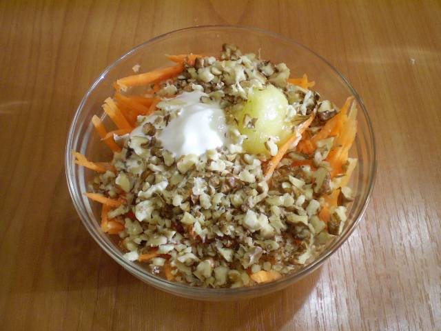 В глубокий салатник сложите морковь, сметану, мед, грецкие орехи. Перемешайте салат.