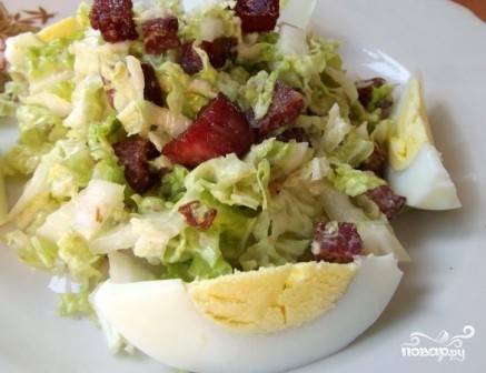 Выкладываем салат на порционную тарелку и добавляем ломтики вареных яиц.